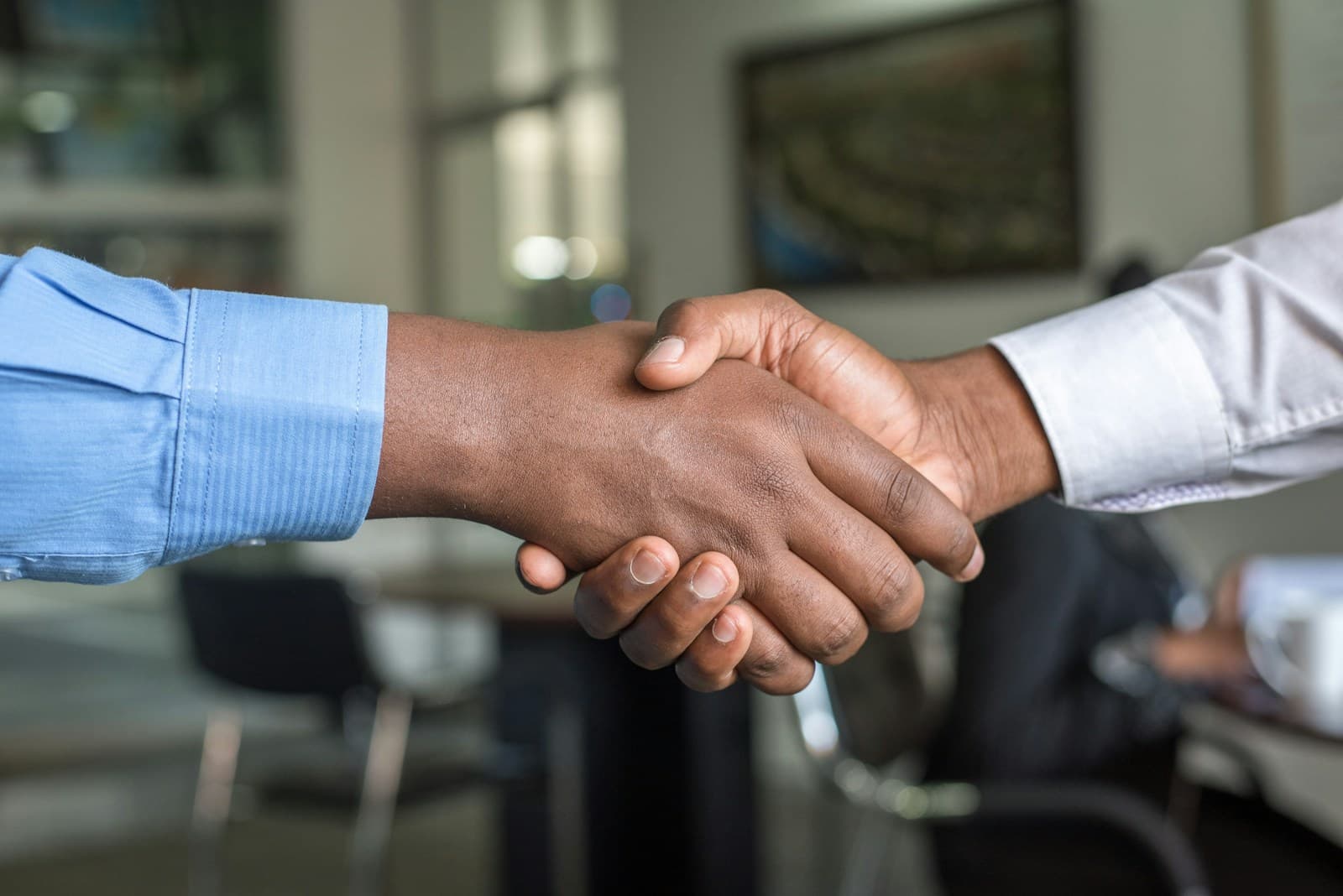 Two professionals shaking hands in an office, symbolizing agreement and a hiring decision.