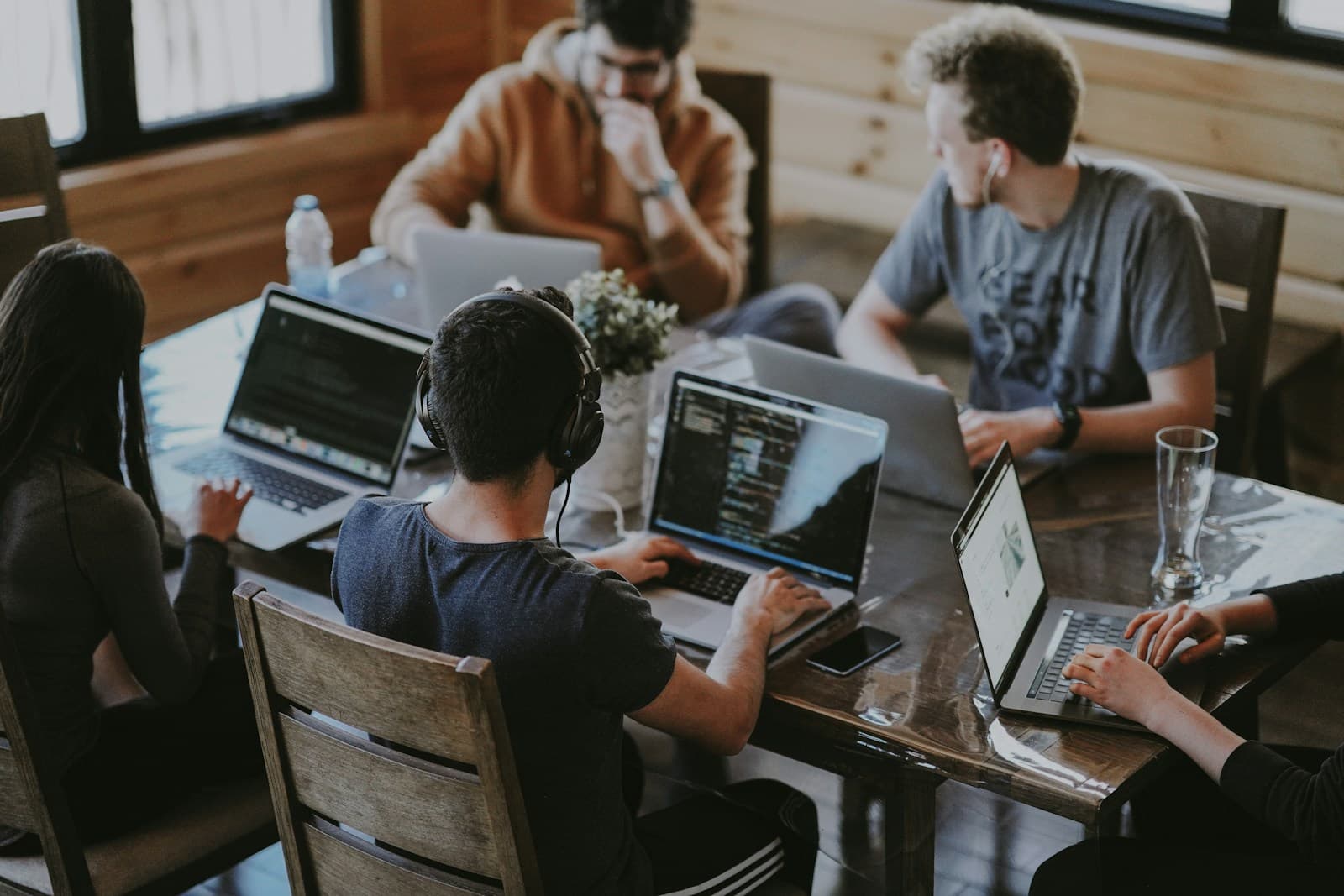 Plusieurs collaborateurs en réunion de travail autour d’ordinateurs, échange et décision collective.